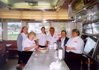 The staff is ready for the Diner's first customers. Julia slices the first pie to be served.